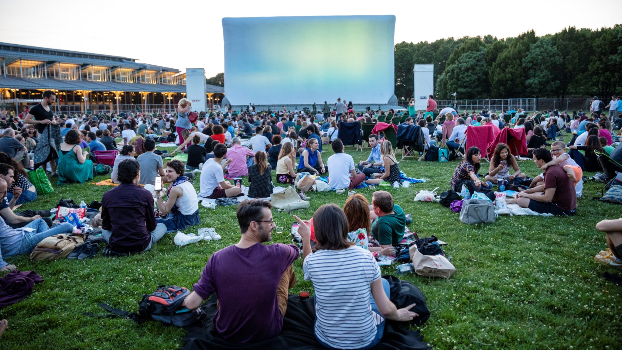 Photo de gens sur une pelouse devant un écran de cinéma